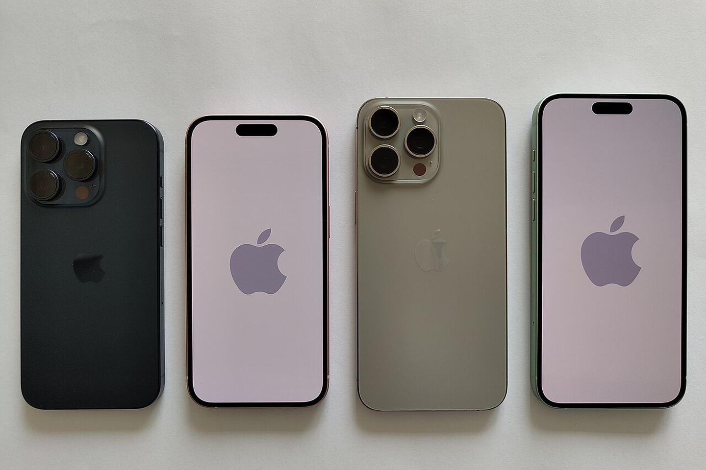 Ілюстративне фото чотирьох iPhone на світлій поверхні: два показані ззаду, два — спереду.